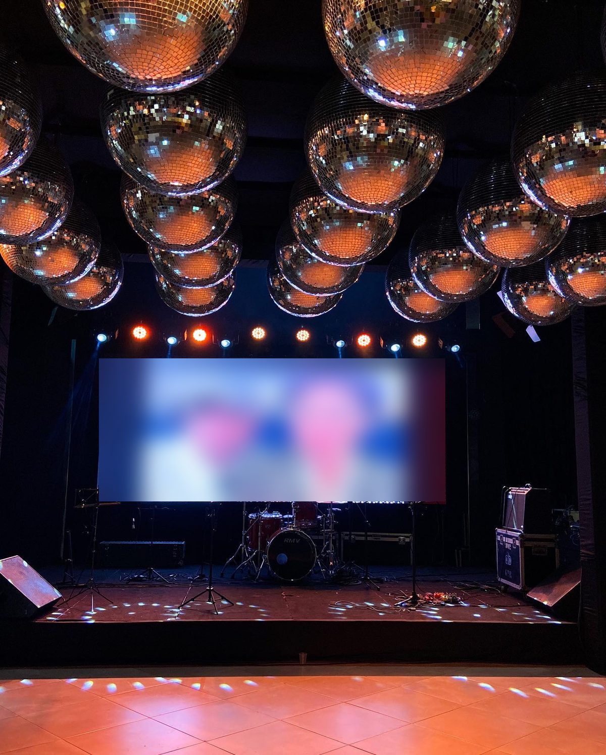 Palco com banda, telão e globos espelhados