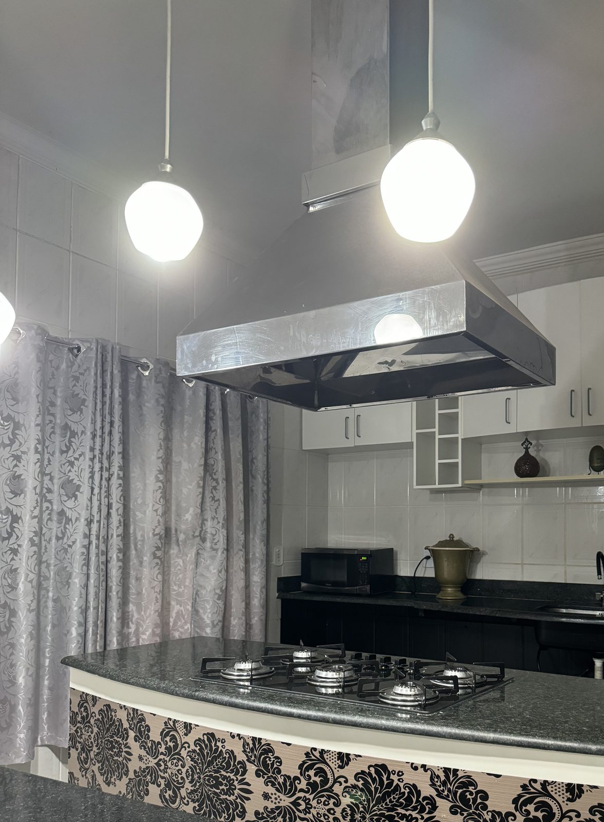 Cozinha equipada com cooktop, coifa e bancada de granito