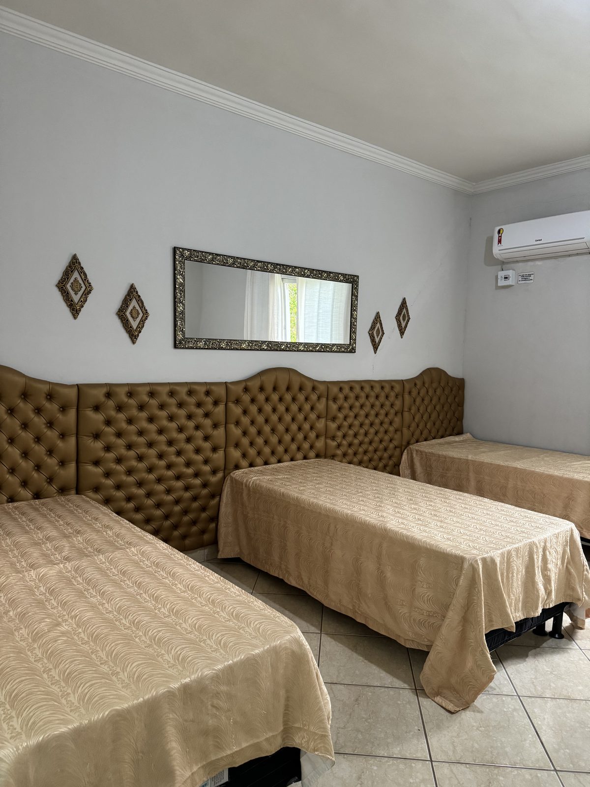 Quarto climatizado com três camas de solteiro