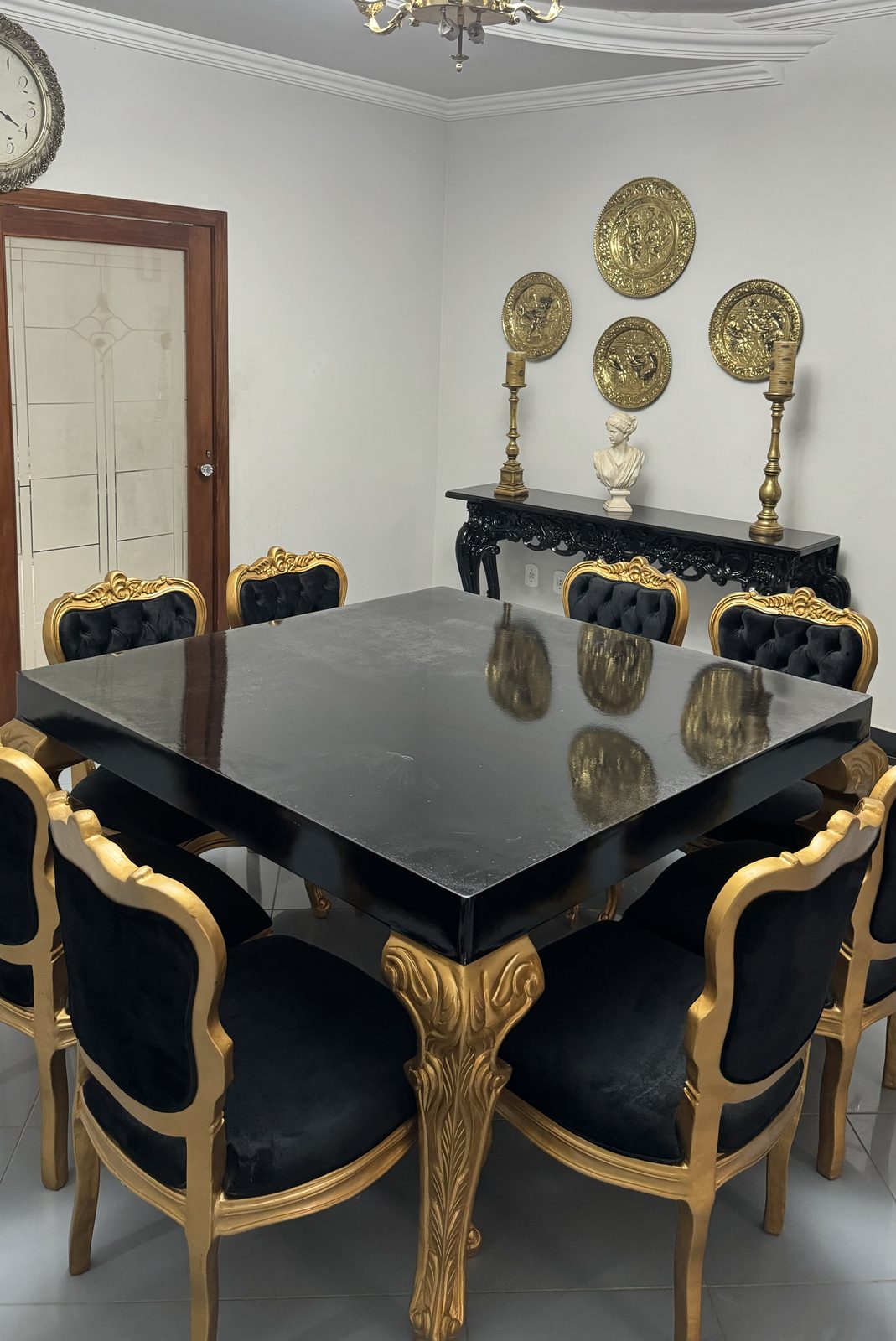 Sala de jantar com mesa preta e cadeiras douradas