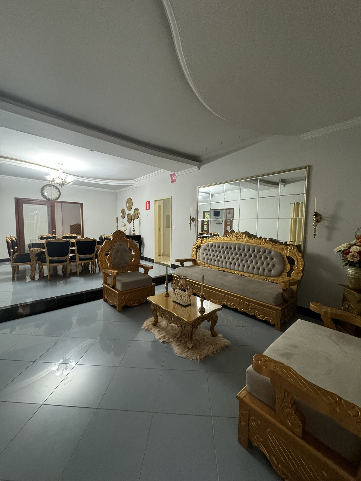 Sala de estar com sofá e poltrona entalhados em dourado e espelho