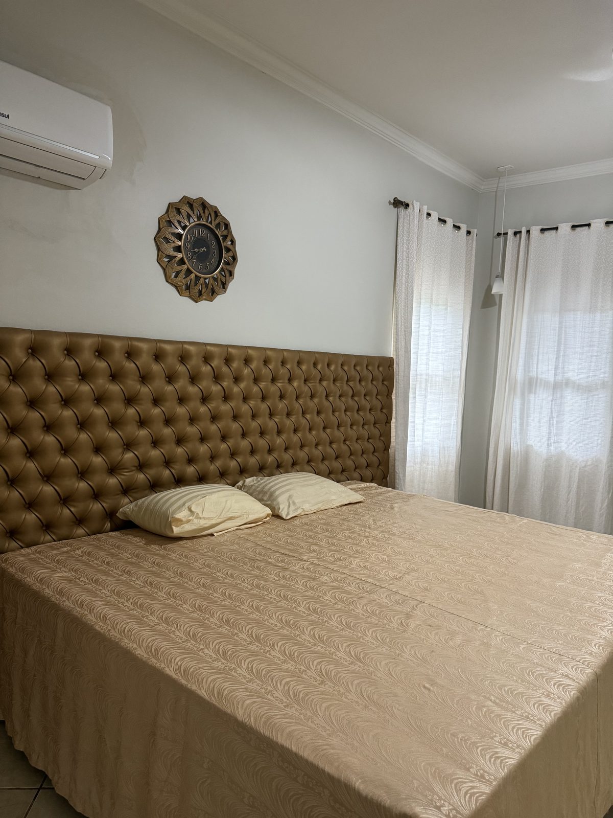 Suíte com cama de casal, cabeceira capitonê e ar-condicionado
