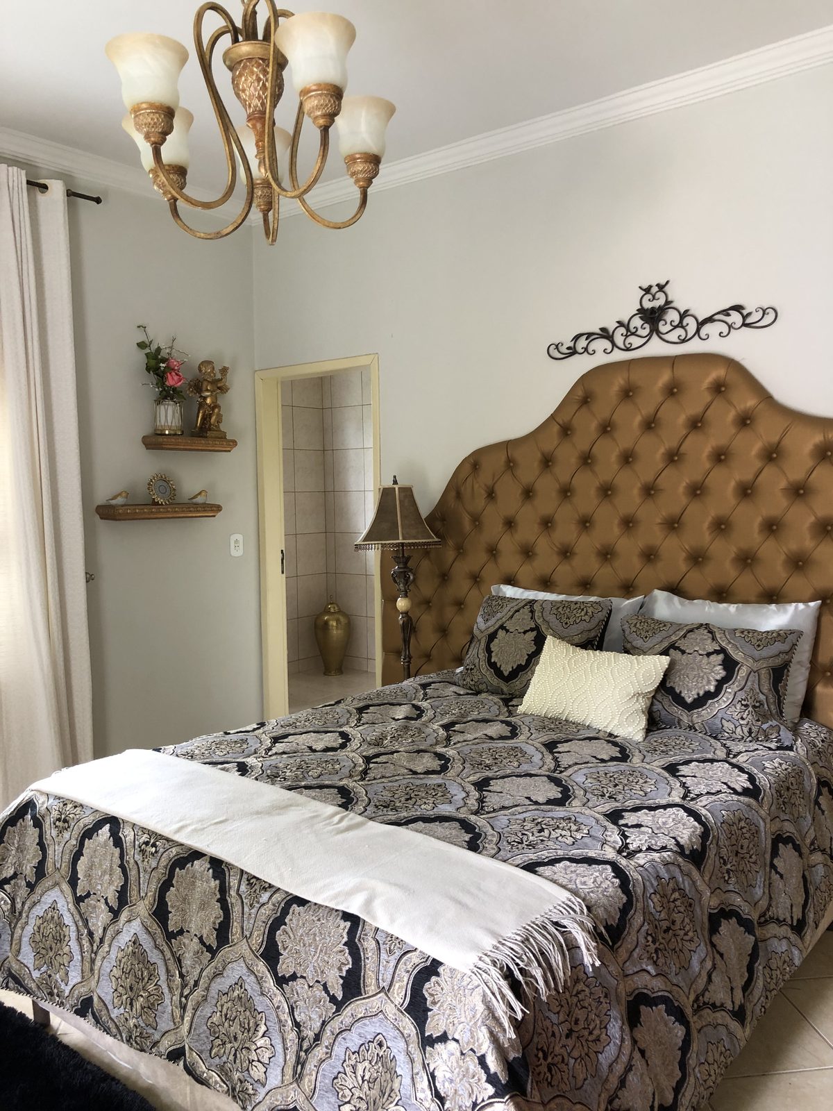 Suíte com lustre, cama de casal e banheiro